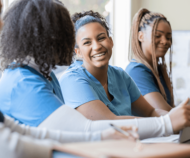 一个护理专业的学生穿着手术服和她的两个同学坐在一起聊天.