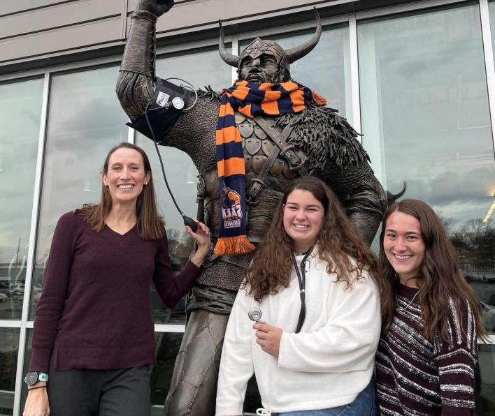 Brett Ely stands with students in front of the Viking statue.