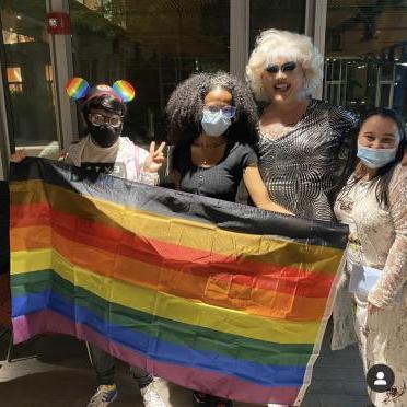 Students gather with a drag performer and a Pride flag at a student event