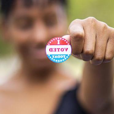 A woman holds up her "I Voted" sticker
