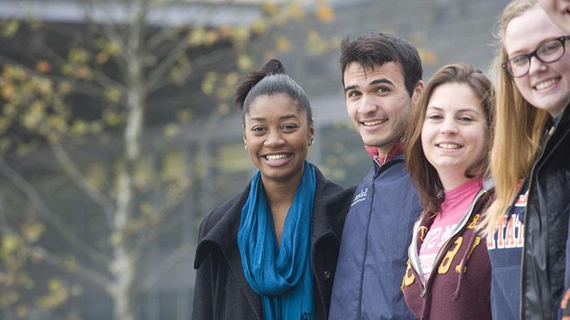 A group of students of diverse backgrounds enjoy a fall day on campus